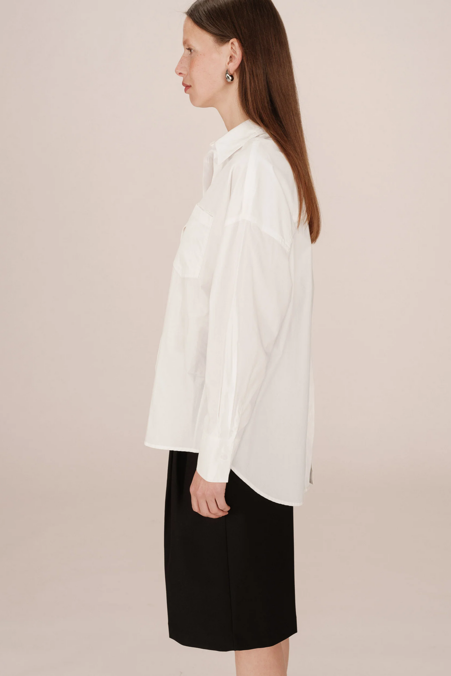 Woman wearing a white blouse and black skirt on a beige background