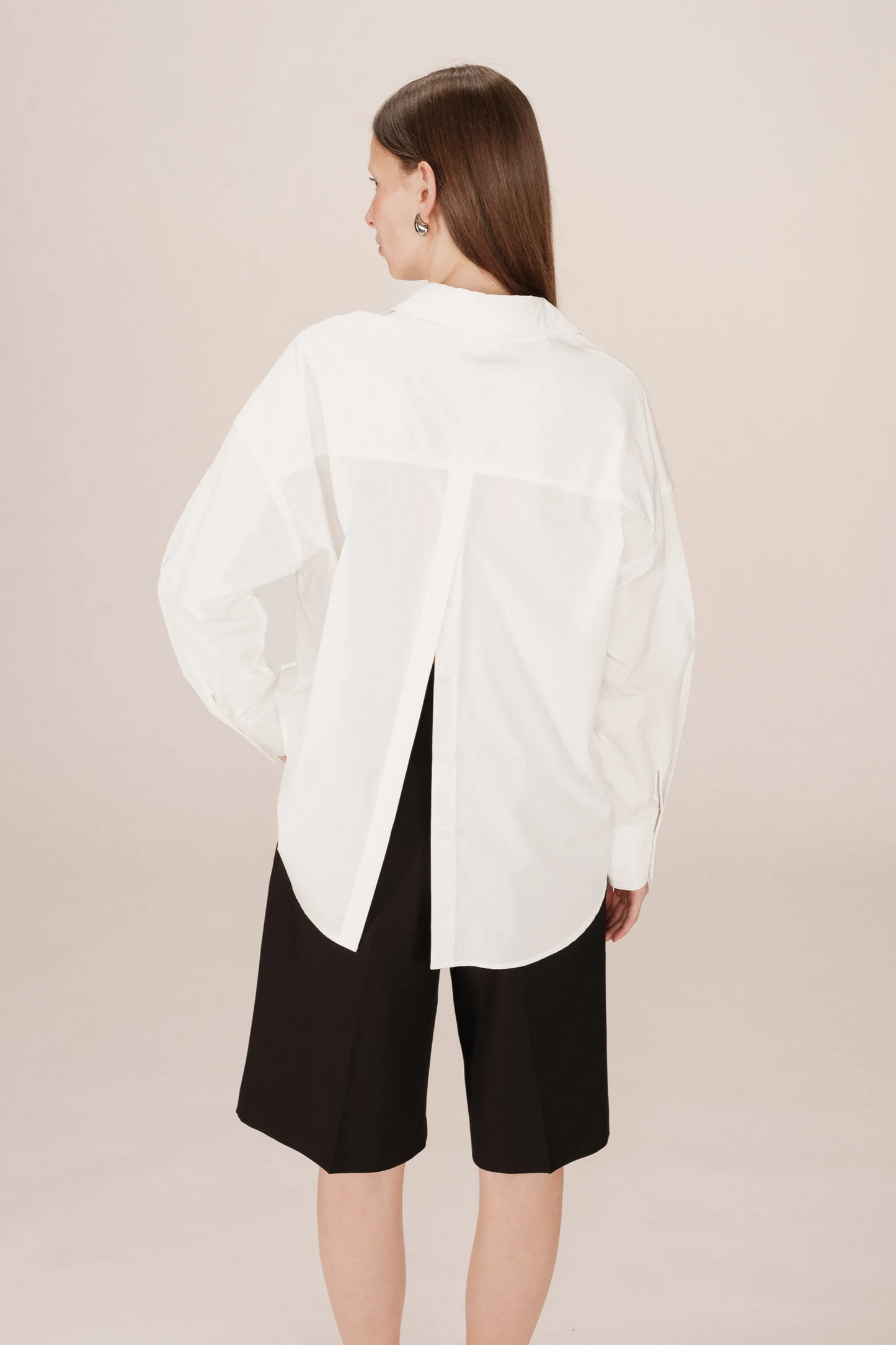 Woman wearing a white blouse and black shorts on a beige background
