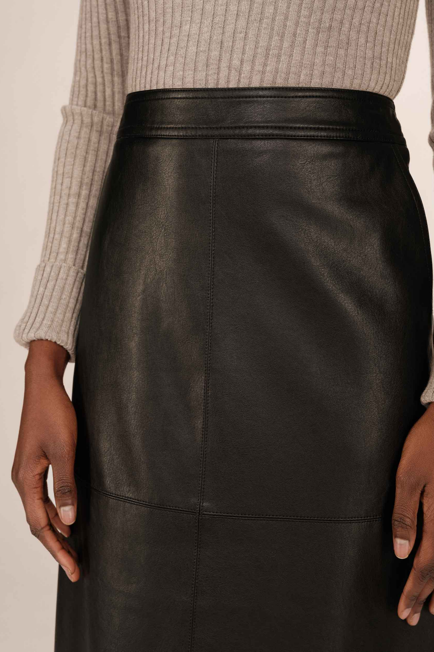 Black leather skirt worn by a person with a neutral background