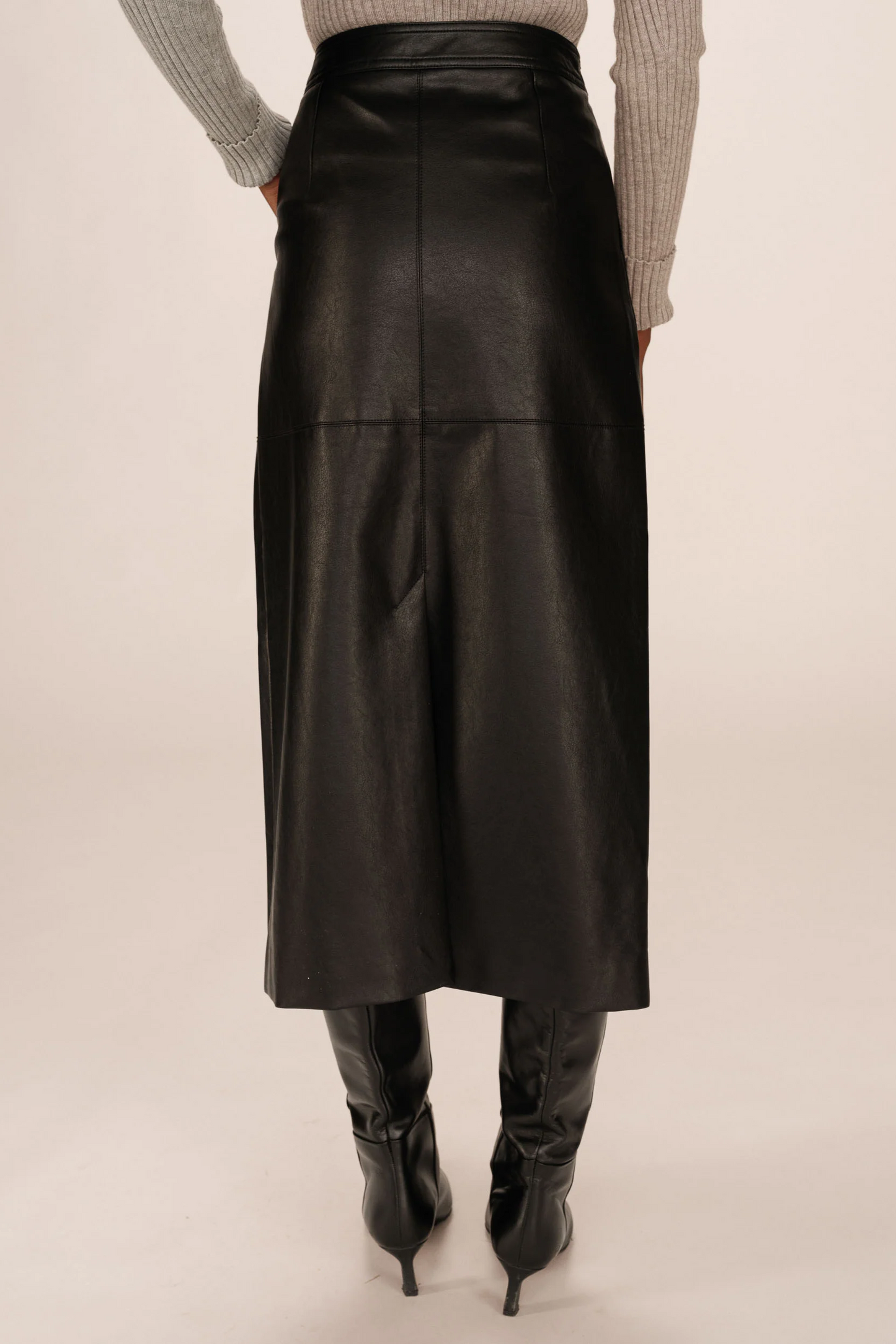 Black leather skirt worn by a person on a plain background