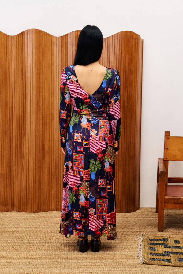 Person wearing a colorful patterned dress standing in front of a wooden screen.