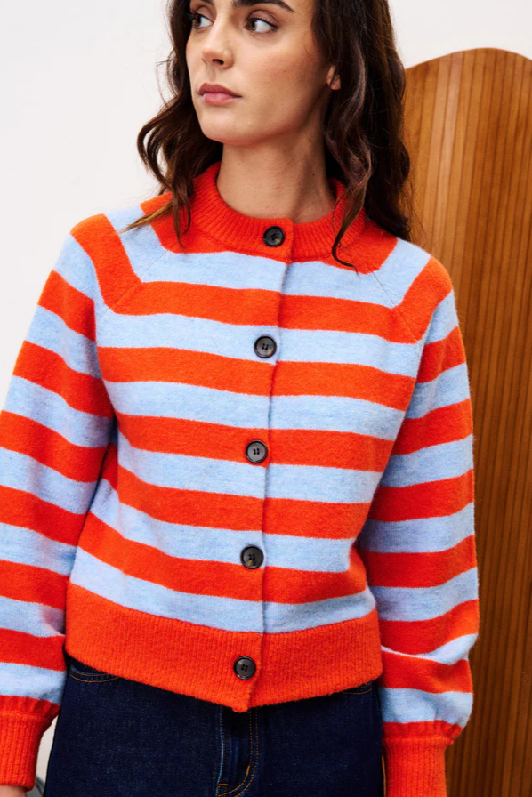 Woman wearing a red and white striped sweater with black buttons against a wooden background