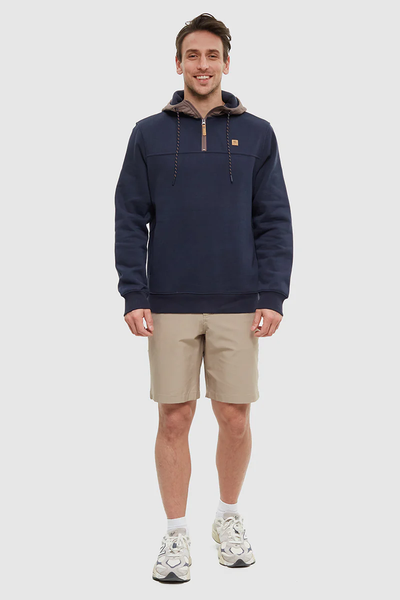 Man wearing a navy hoodie with a brand logo on a white background