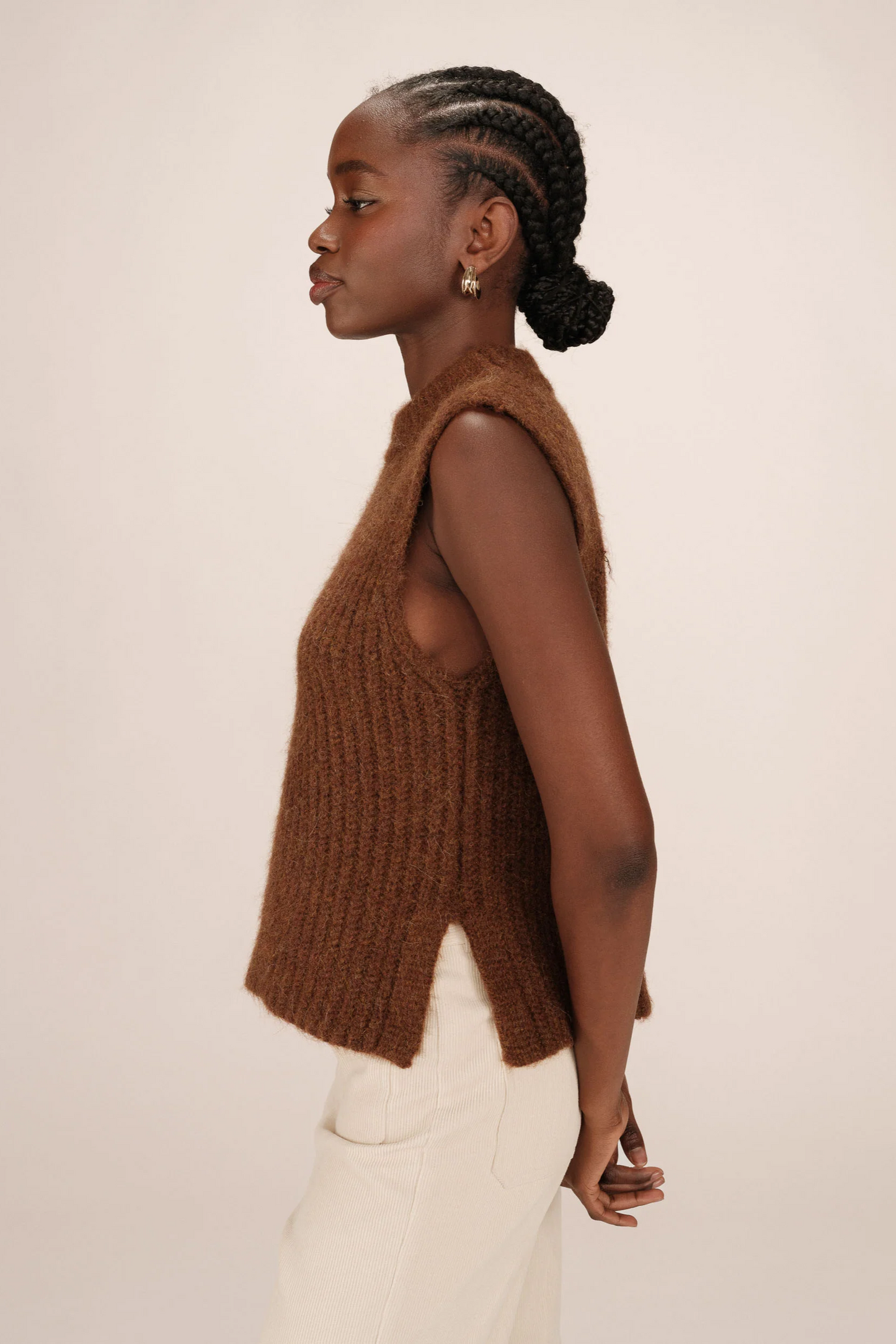 Woman wearing a brown knitted vest against a plain background