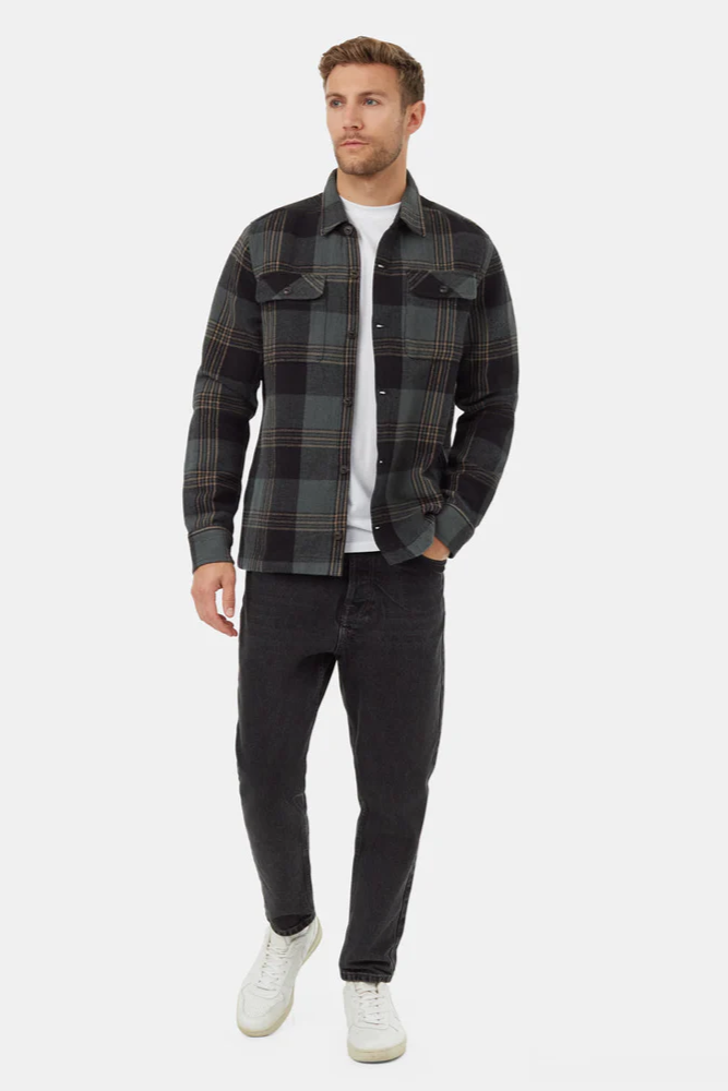Man wearing a plaid shirt over a white t-shirt with dark jeans on a white background