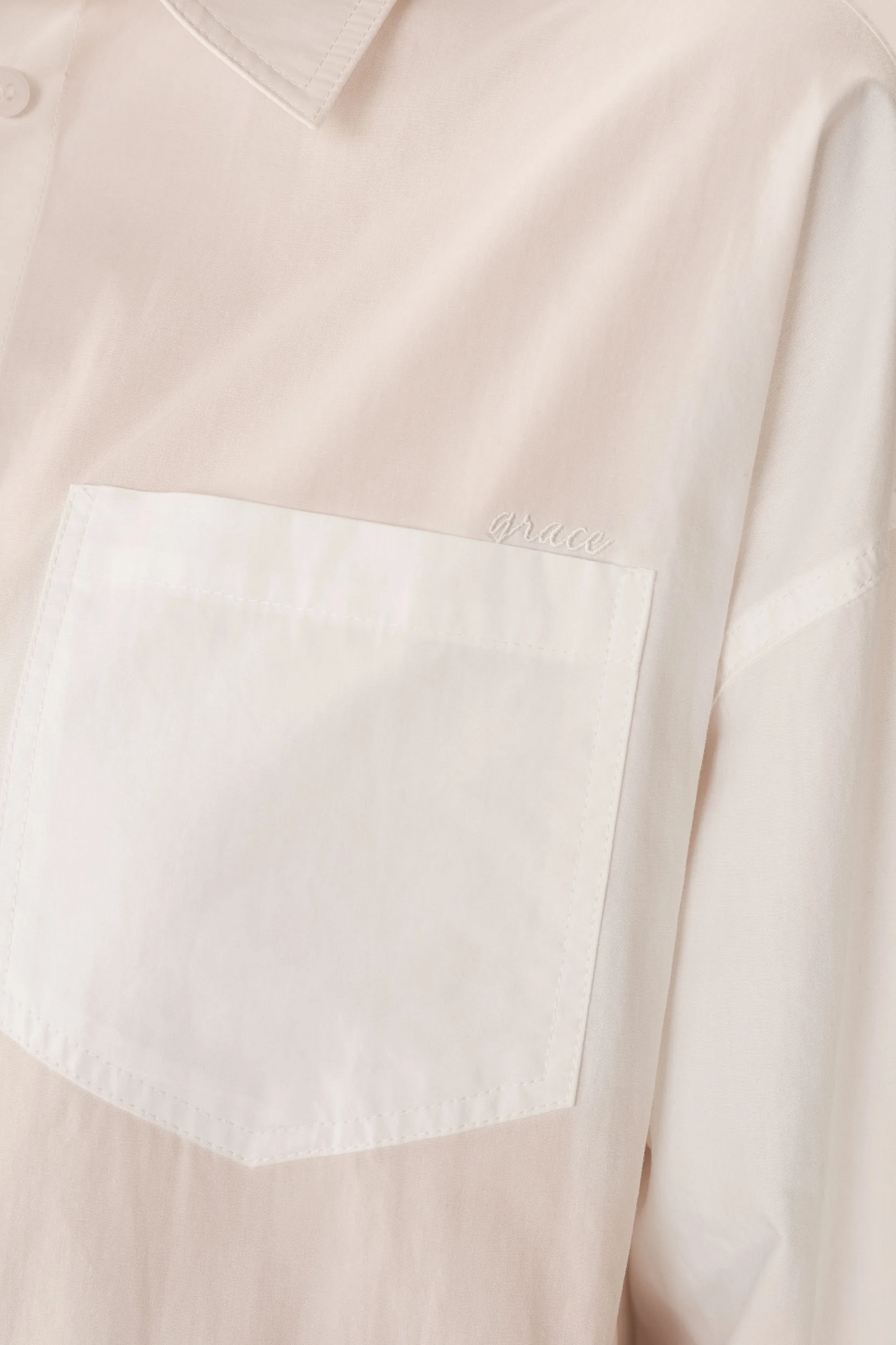 Close-up of a light pink shirt with a white pocket detail.