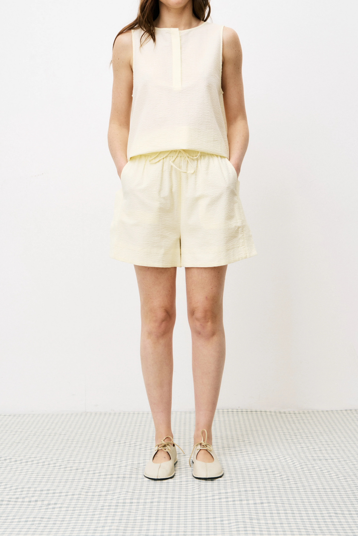 Person wearing a white sleeveless top and shorts on a white background