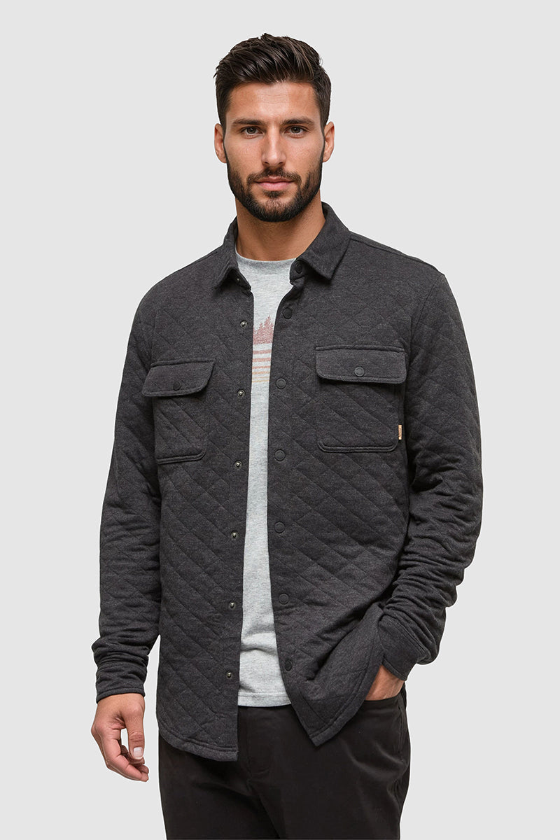 Man wearing a dark gray quilted jacket on a light gray background