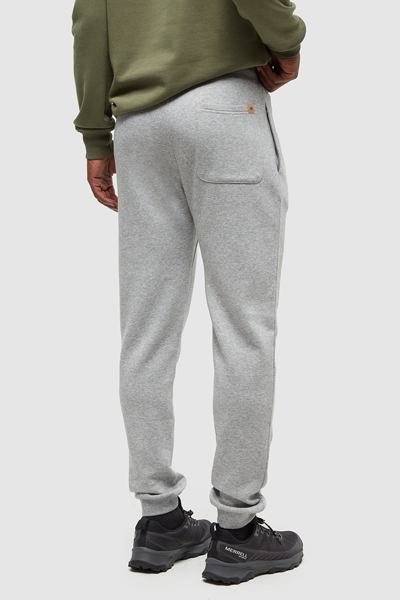Person wearing gray sweatpants and a green sweatshirt on a white background