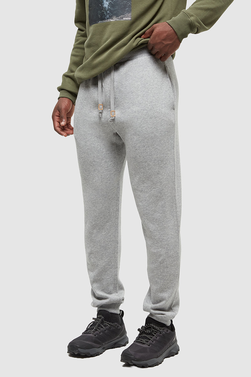 Person wearing gray sweatpants and a green hoodie on a white background