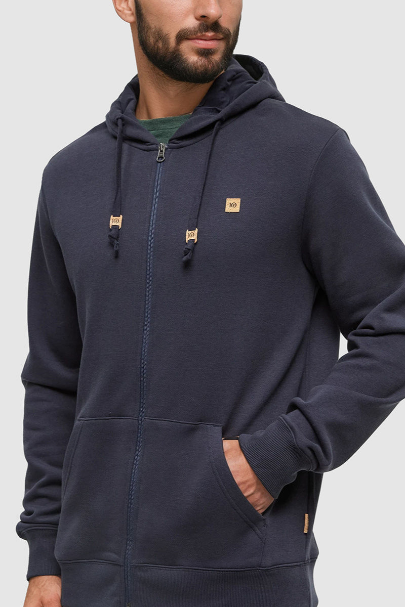 Man wearing a navy blue hoodie with a brand logo on a light gray background