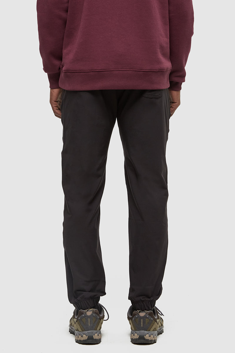 Person wearing a maroon hoodie and black pants on a white background