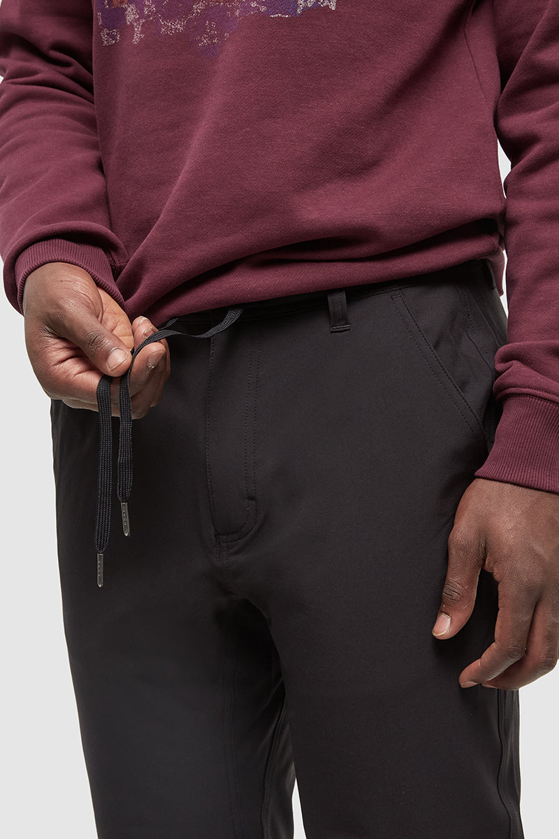 Person wearing a maroon hoodie and black pants on a light gray background
