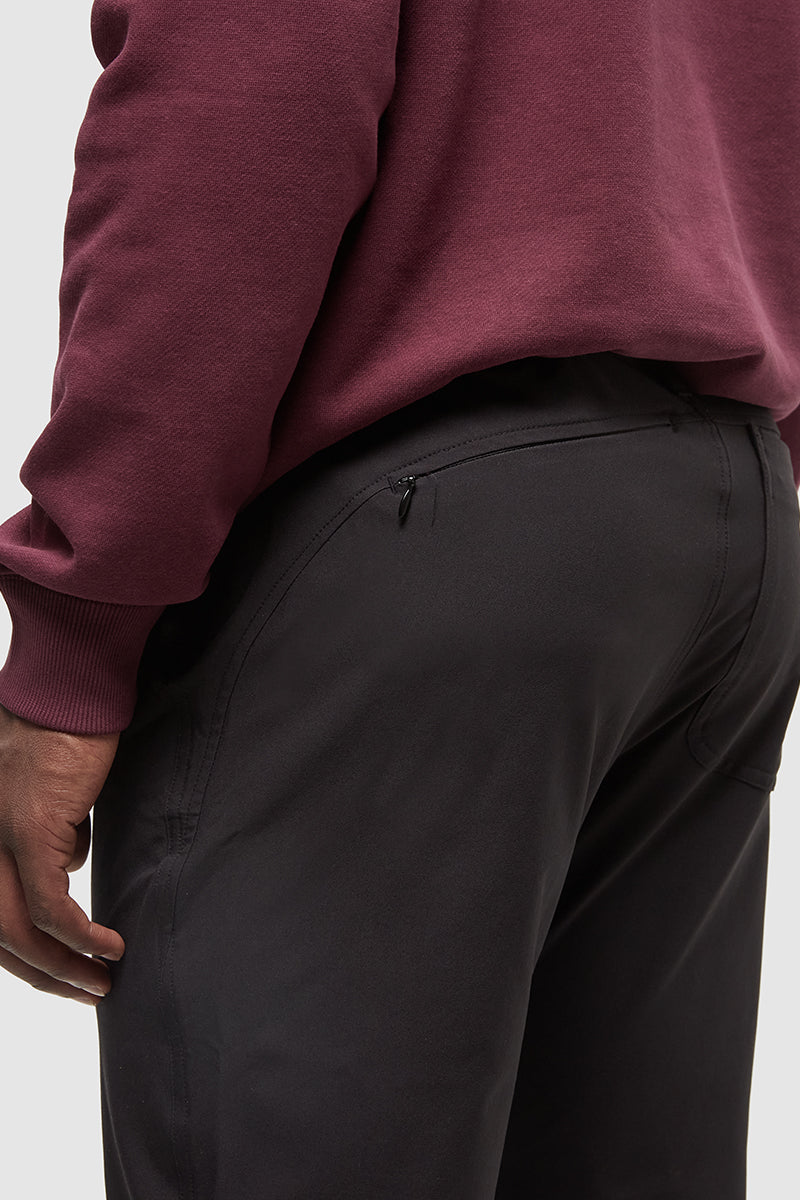 Person wearing a maroon sweatshirt and dark pants on a white background