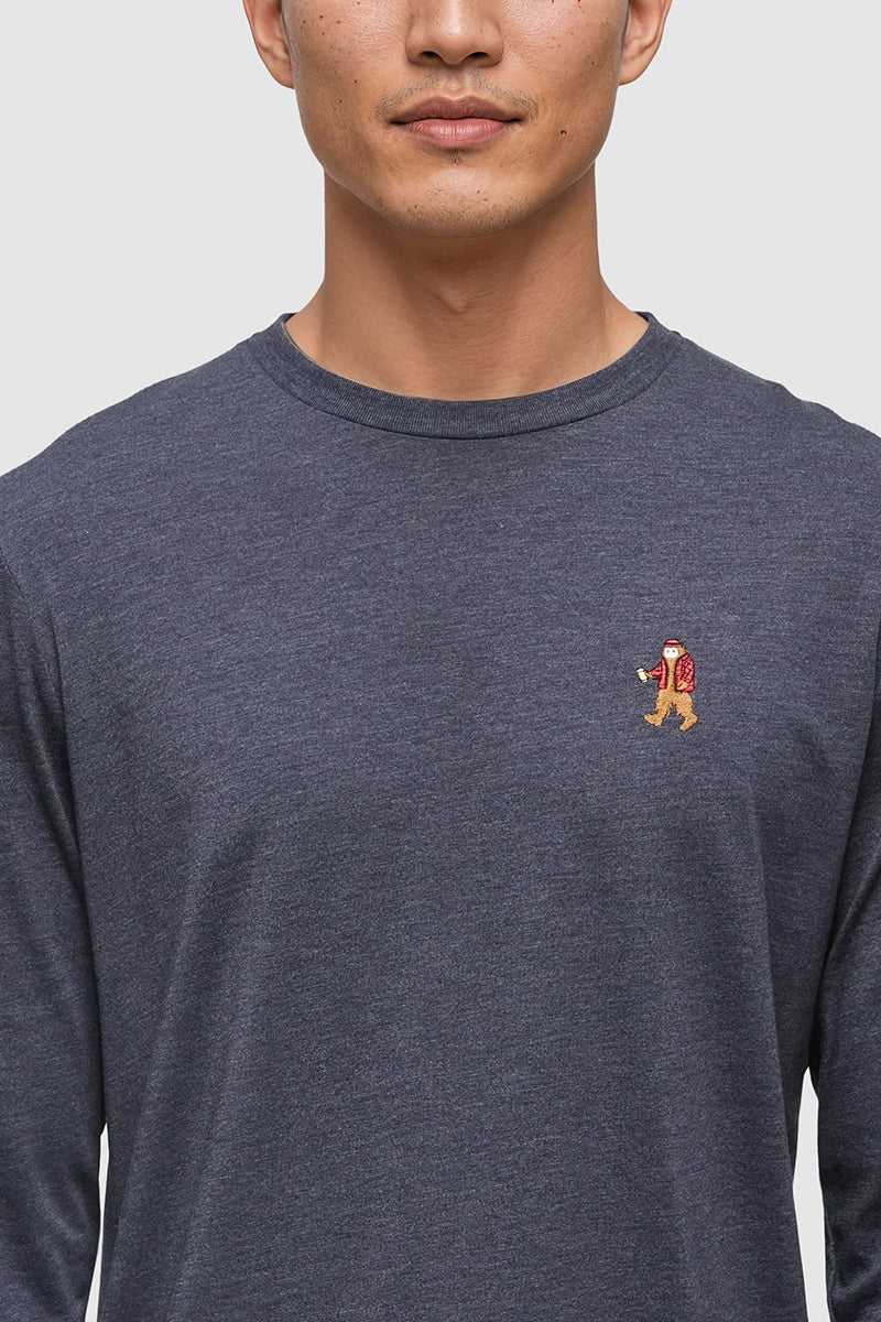 Person wearing a dark gray long-sleeve shirt with a small logo on the chest against a plain background