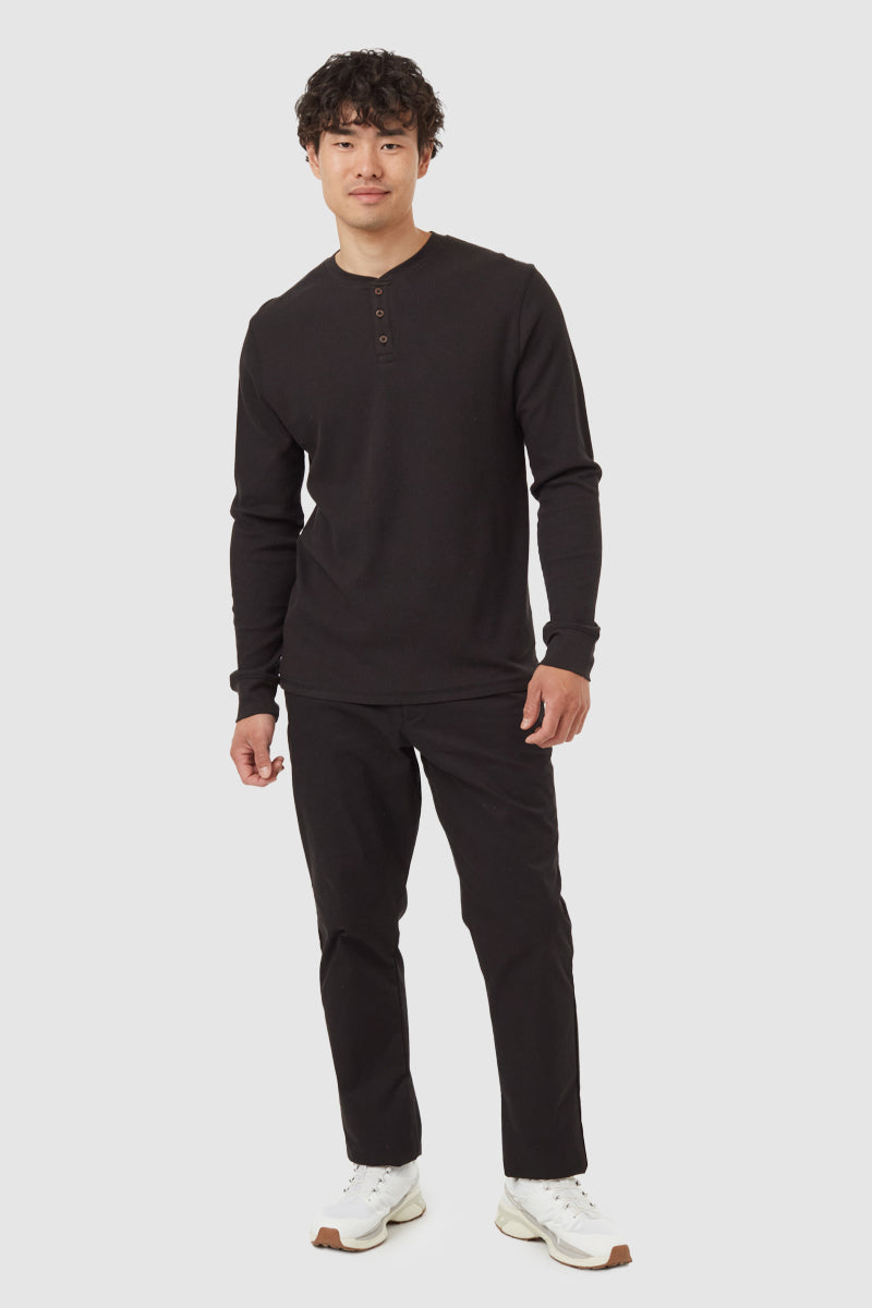 Man wearing a black long-sleeve shirt and pants on a white background
