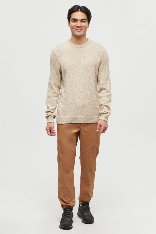 Man wearing a beige sweater and brown pants on a white background