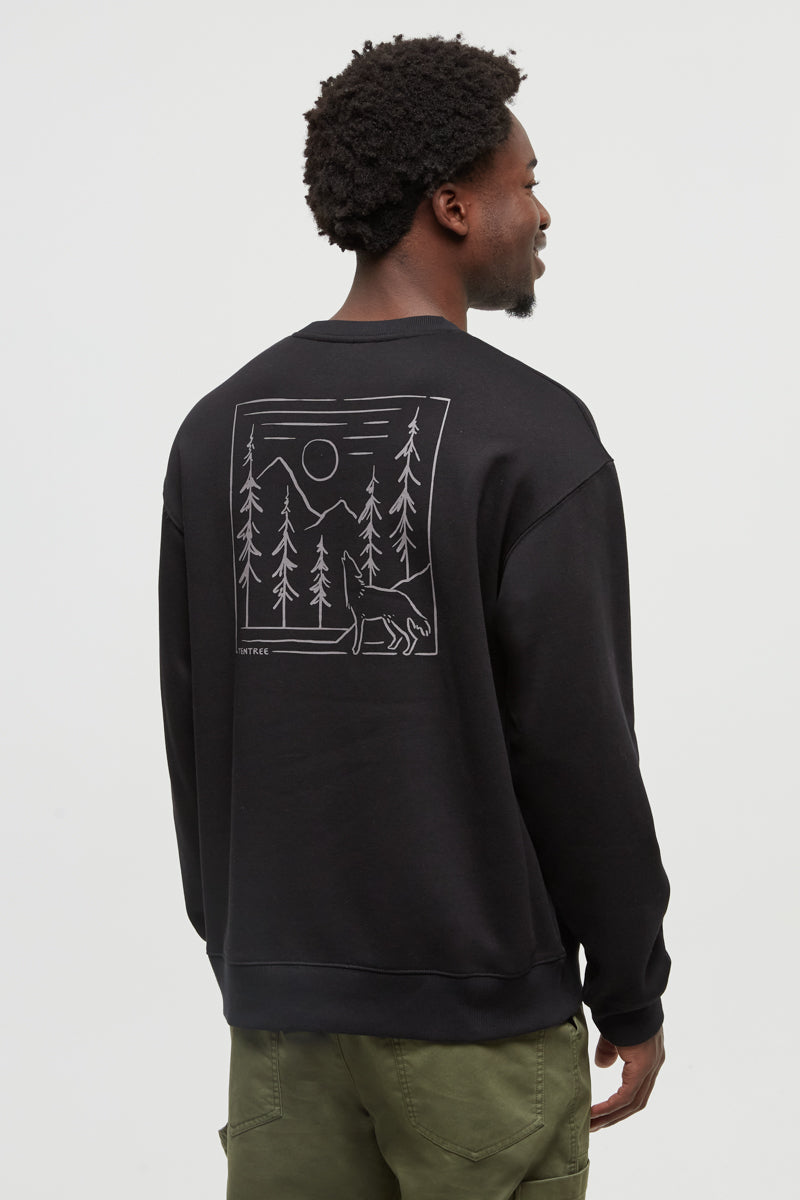 Person wearing a black sweatshirt with a graphic design on the back, standing against a white background