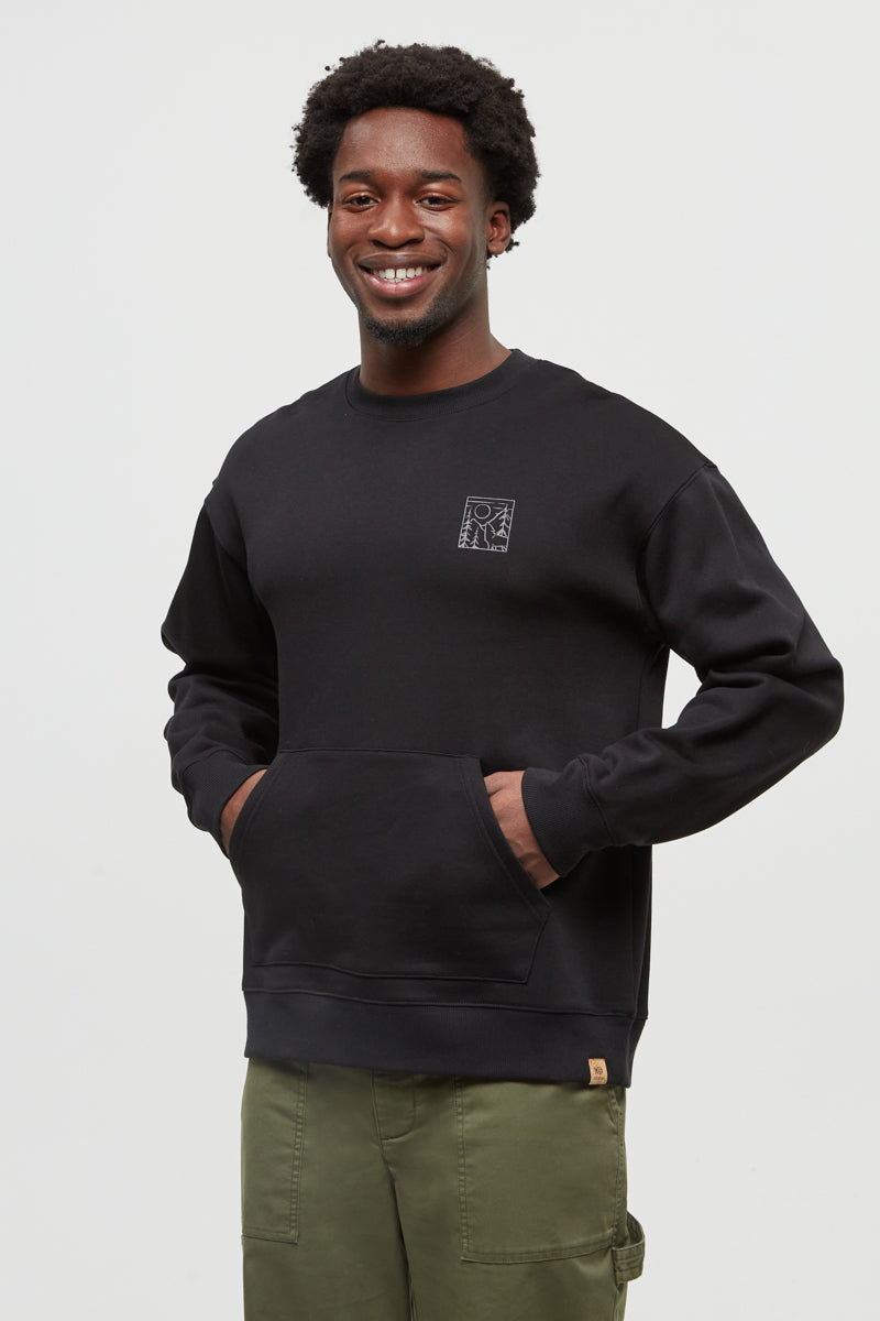 Man wearing a black sweatshirt with a logo on a plain background
