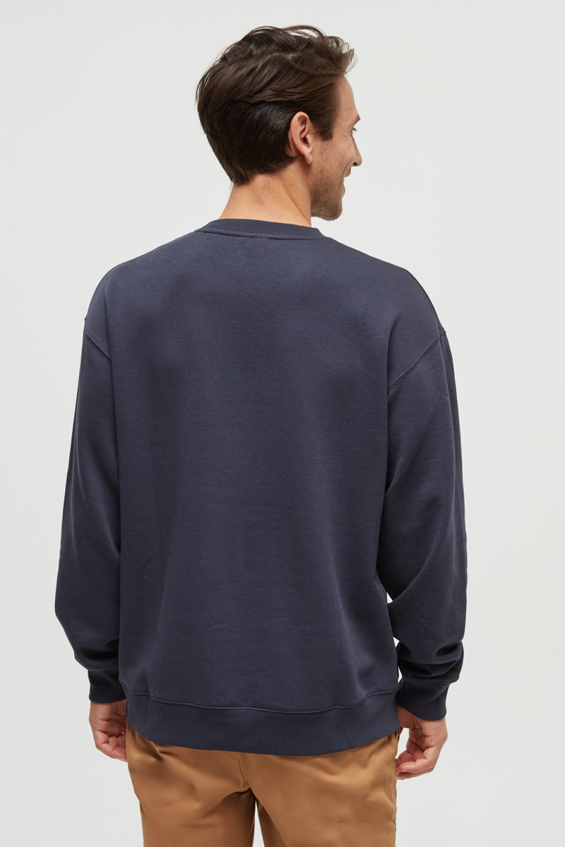 Man wearing a navy blue sweatshirt on a light gray background