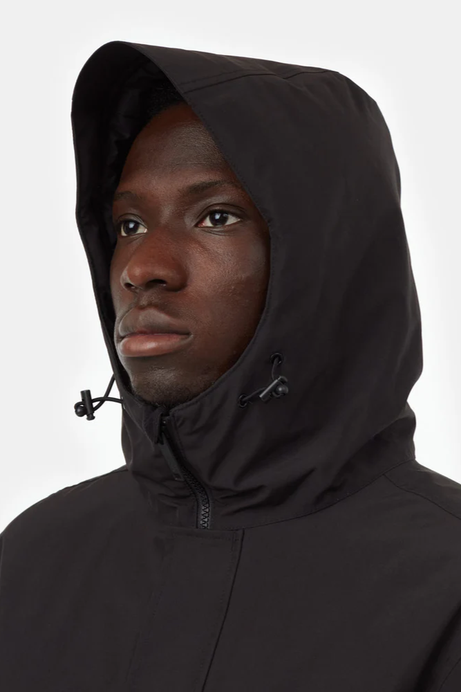 Person wearing a black hooded jacket on a white background