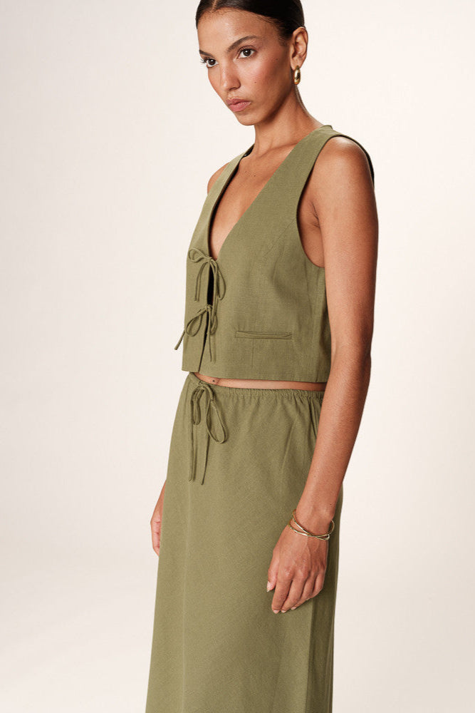 Woman wearing a green sleeveless dress against a white background