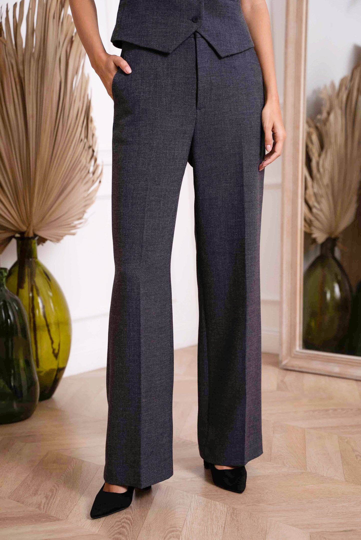 Person wearing a navy suit with wide-leg pants in an indoor setting.