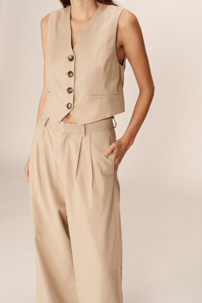 Beige vest and pants set on a plain background