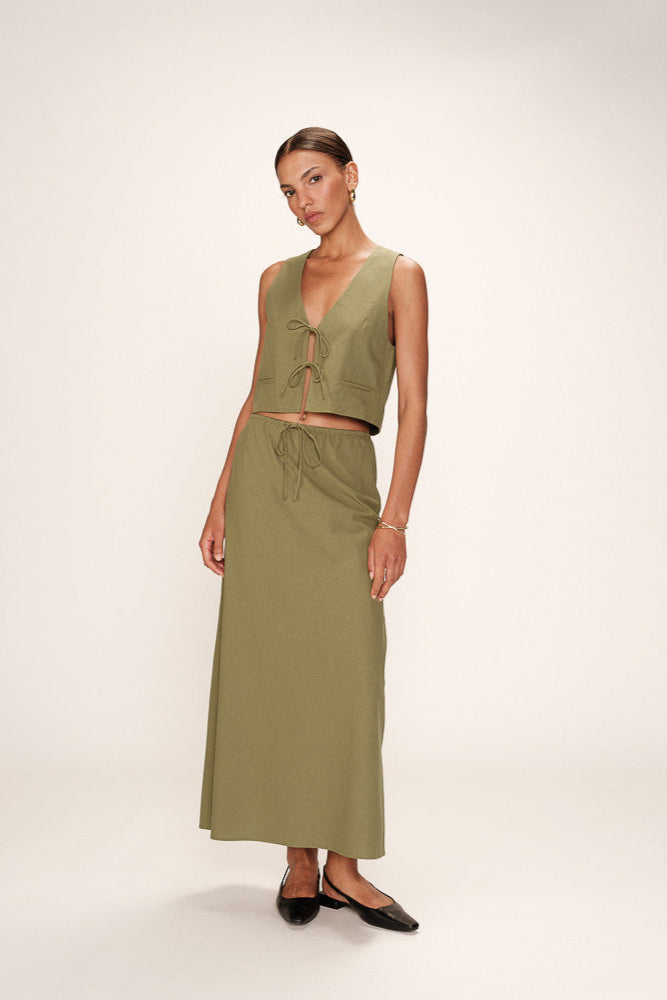Woman wearing a green sleeveless top and skirt set on a white background