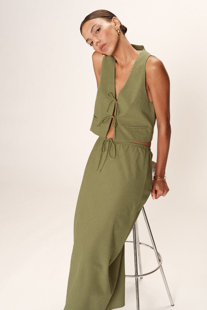 Woman wearing a green sleeveless jumpsuit on a white background