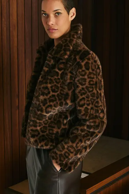 Person wearing a leopard print coat in an indoor setting