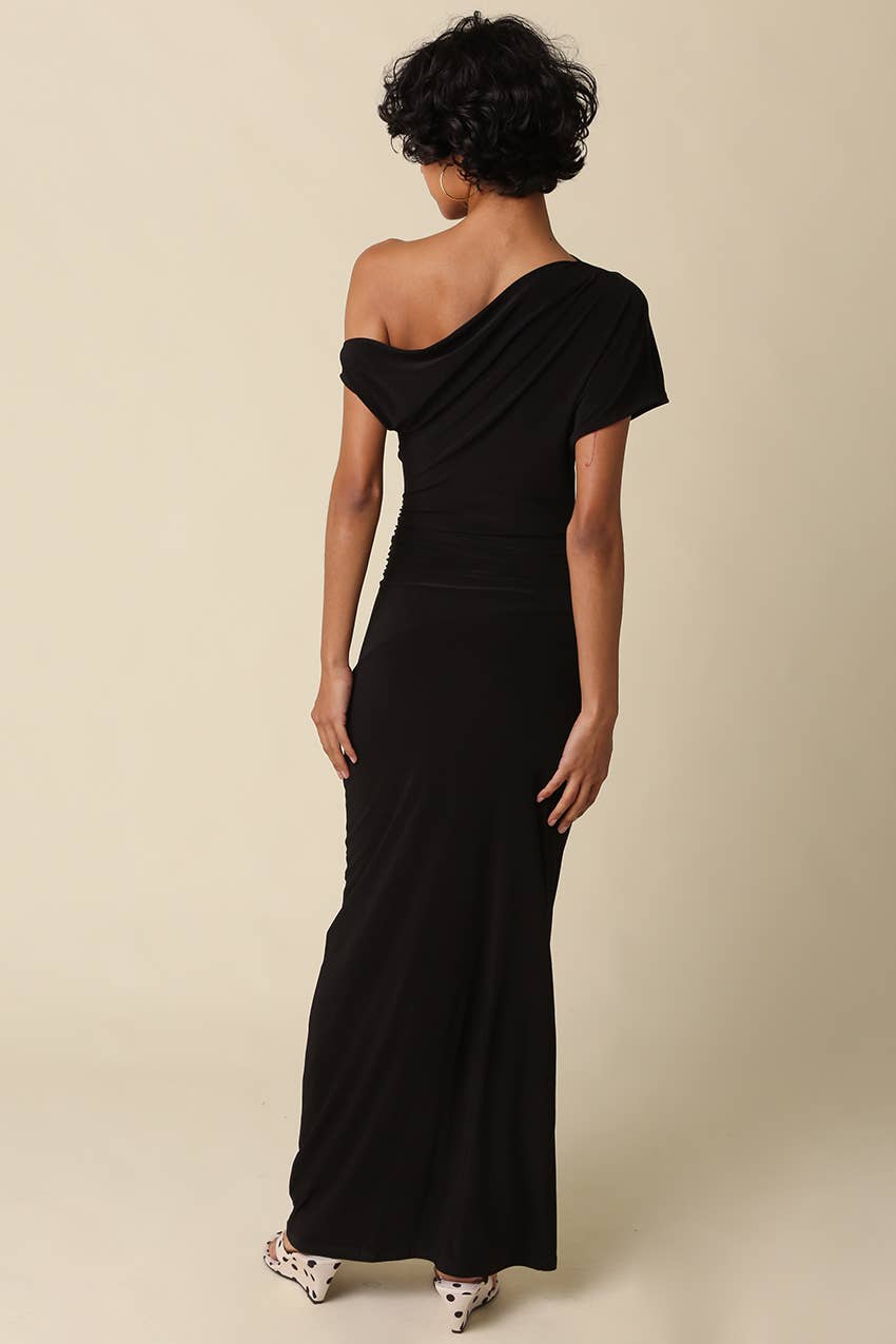 Woman wearing a black one-shoulder gown against a beige background