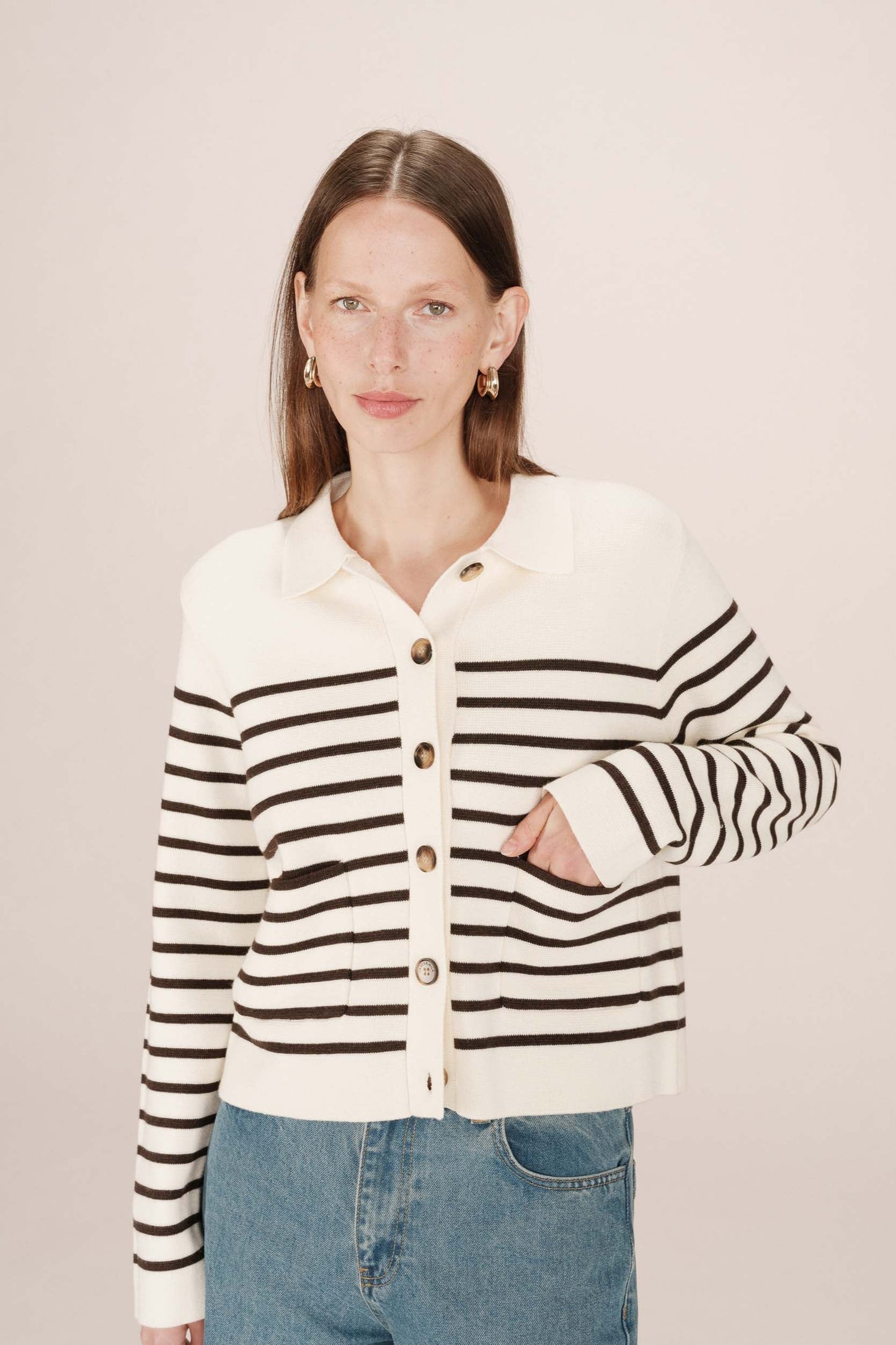 Woman wearing a black and white striped cardigan on a plain background