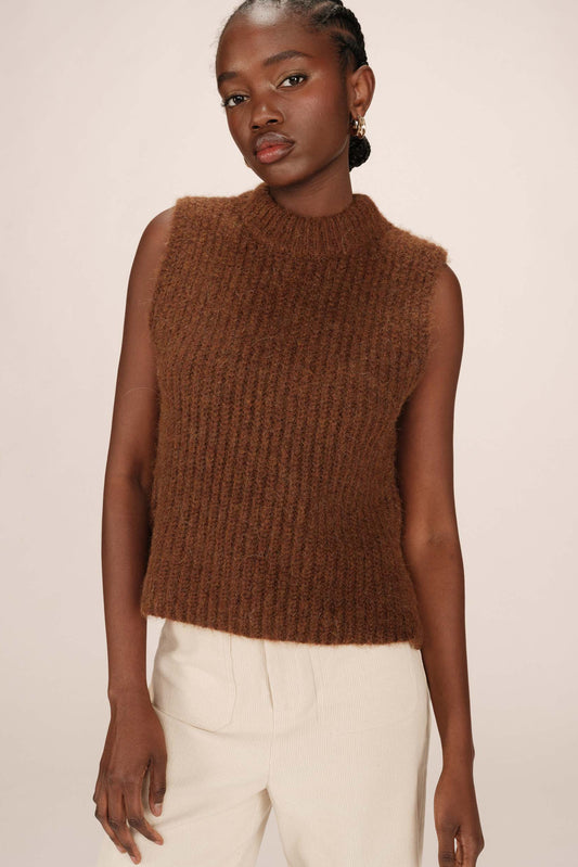 Woman wearing a brown knitted sleeveless sweater against a plain background