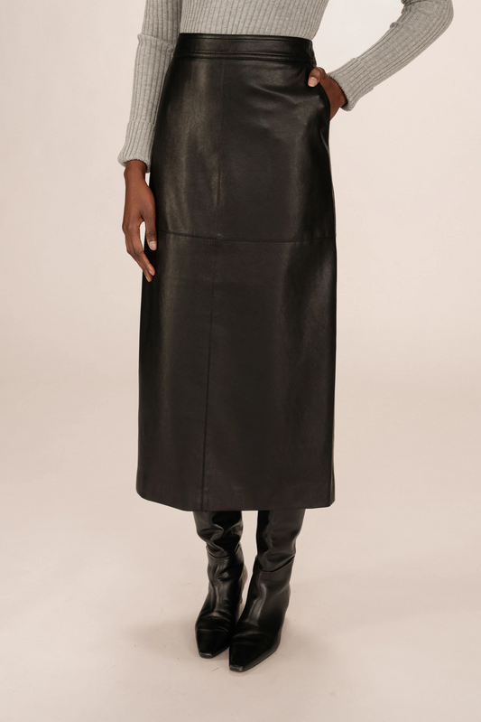 Person wearing a black leather skirt on a beige background