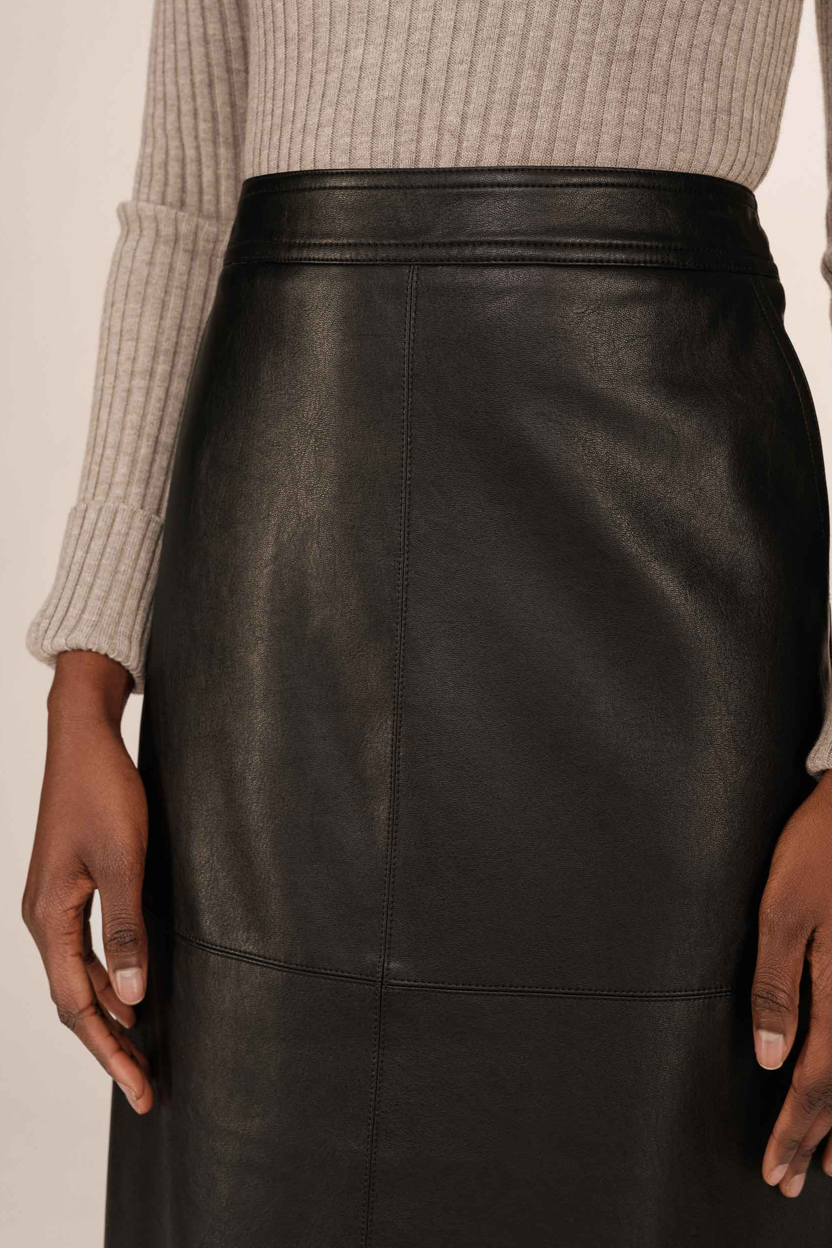 Black leather skirt worn by a person with a neutral background