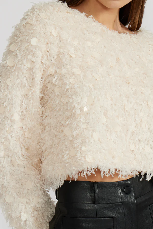 Close-up of a textured white top worn by a person with a blurred background