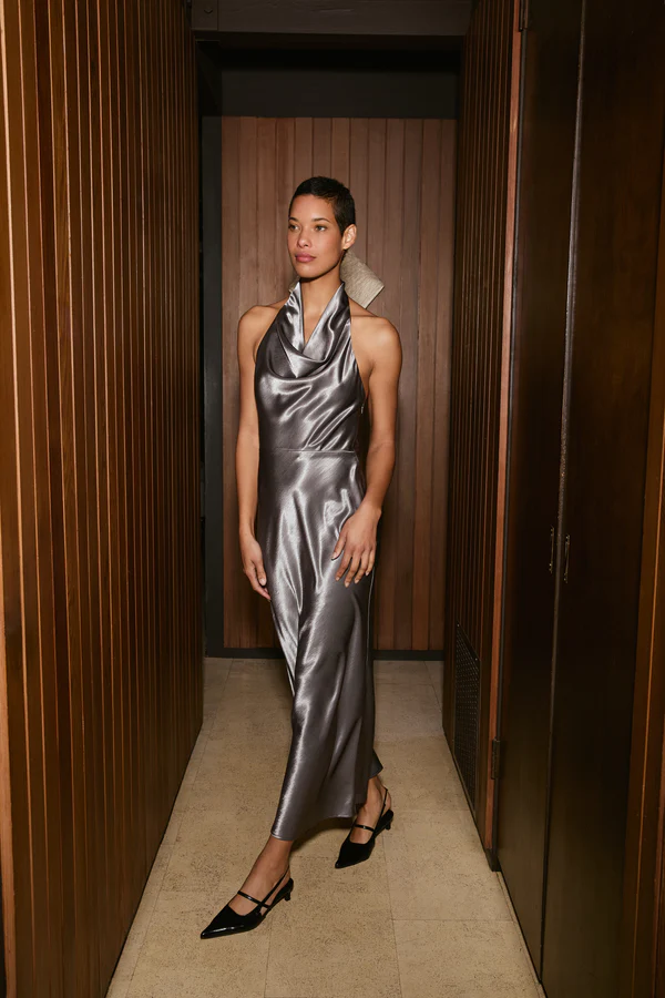 Woman wearing a silver metallic dress in a hallway with wooden walls.
