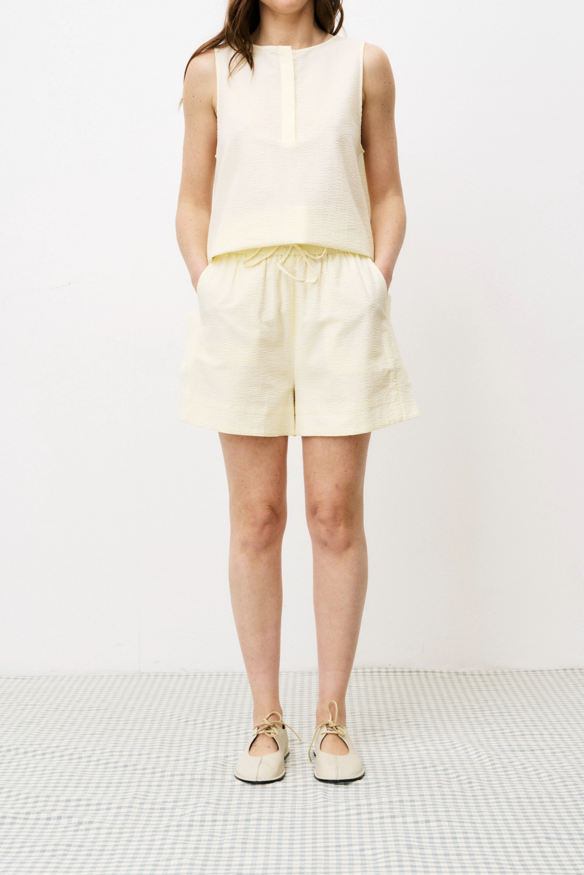 Person wearing a white sleeveless top and shorts on a white background