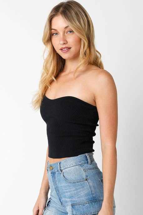 Woman wearing a black strapless top and blue jeans on a white background