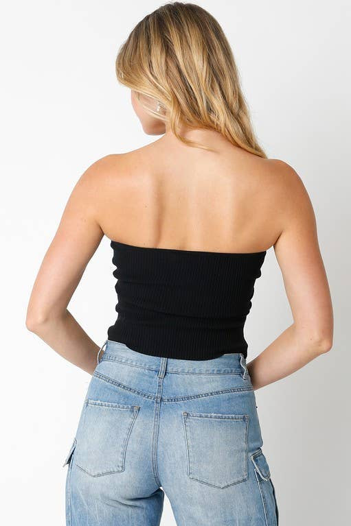 Person wearing a black strapless top and blue jeans on a plain background