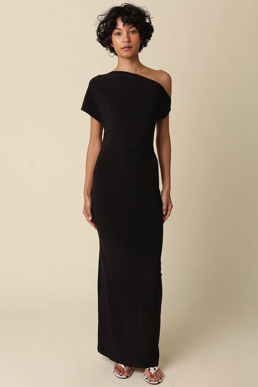 Woman wearing a black one-shoulder dress against a beige background