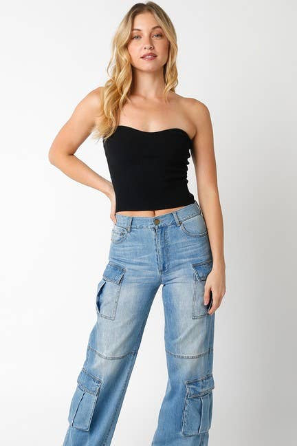 Woman wearing blue cargo pants and a black top on a white background