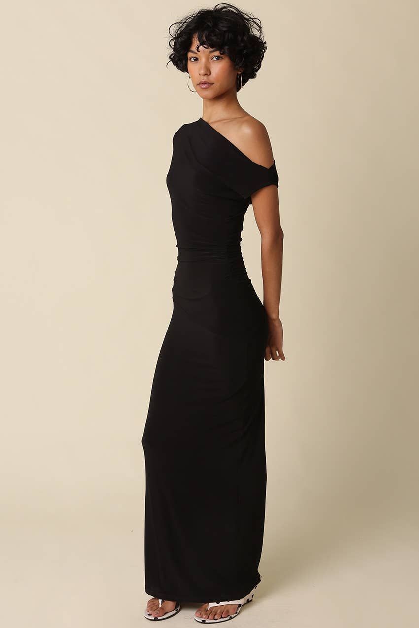Woman wearing a black one-shoulder dress against a beige background