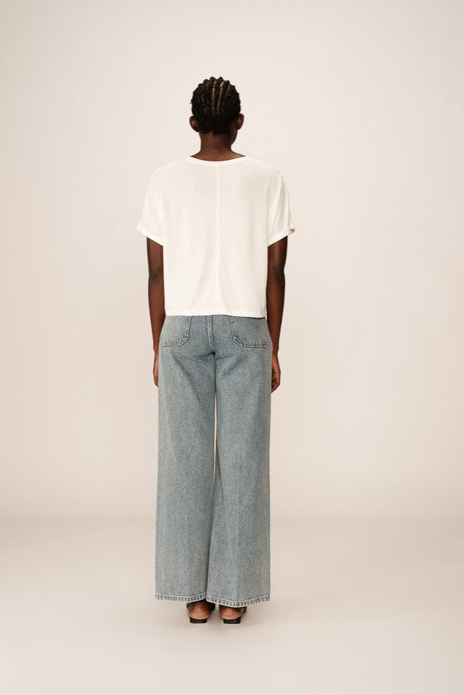 Person wearing a white t-shirt and light blue jeans on a plain background